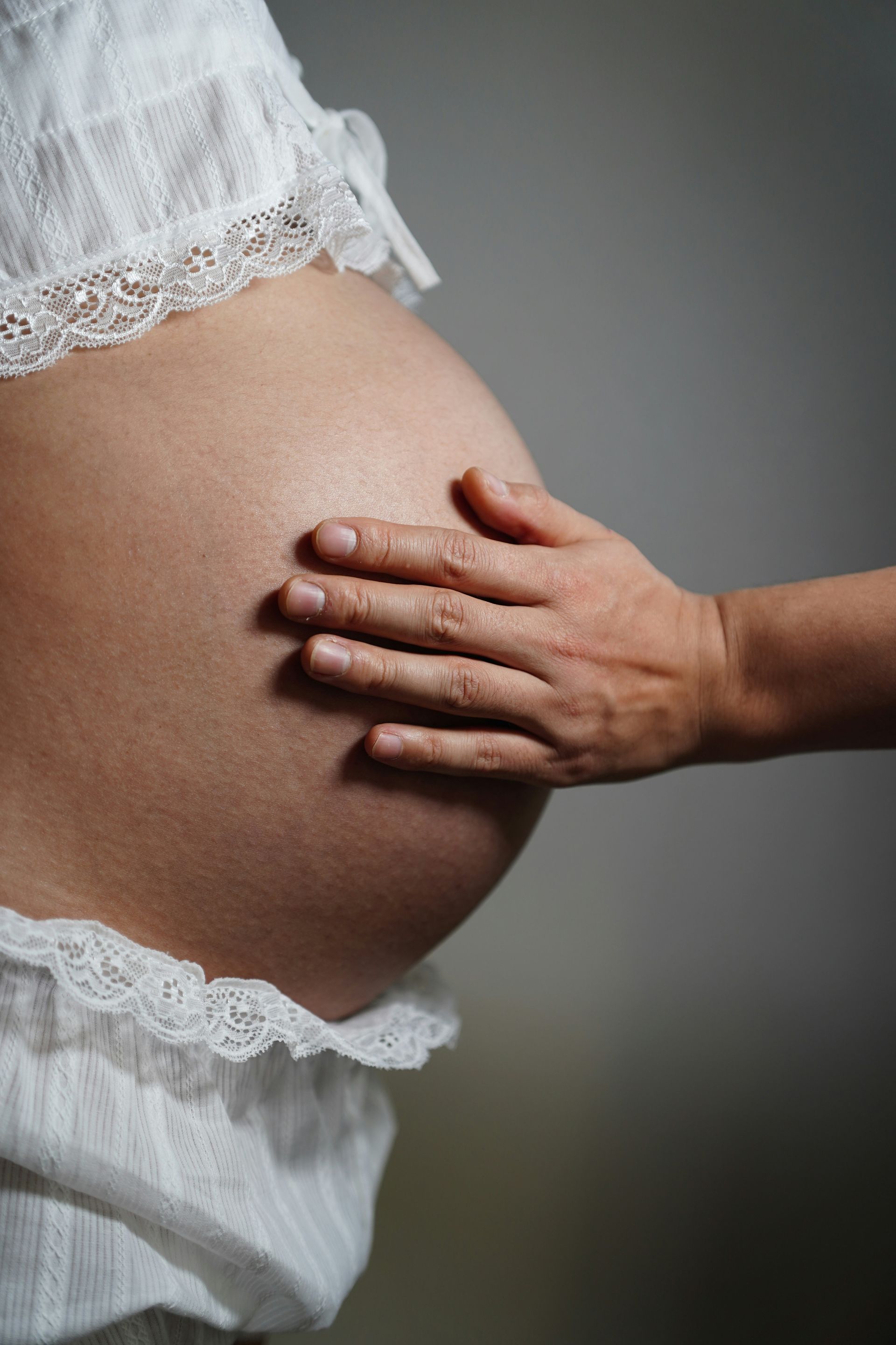 A hand rests gently on a pregnant belly
